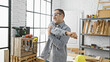 © Krakenimages.com - Hispanic man stretching in a bright carpentry workshop with tools