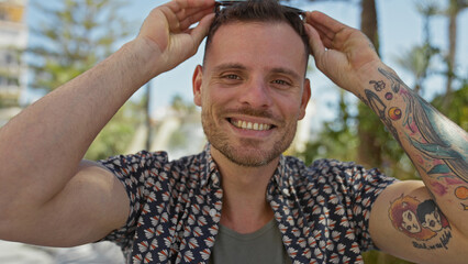 Poster - Smiling tattooed hispanic man with sunglasses in a sunny city park