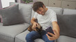 © Krakenimages.com - A cheerful man sitting on a sofa pets a cat while taking a selfie in a cozy living room setting.