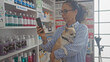 © Krakenimages.com - Middle-aged woman holding a chihuahua, using smartphone in a well-stocked pharmacy