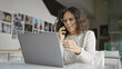 © Krakenimages.com - A mature woman engages in a phone conversation while working on a laptop in a modern office setting.