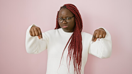 Sticker - A sad african american woman with braids in a white sweater gestures downward against a pink background