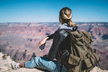 Wall Mural - young female tourist looking at beautiful scenery landscape of grand canyon sitting on peak hill,rea