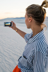 Wall Mural - hipster girl holding mobile phone making picture visiting famous american landmark white sands park 