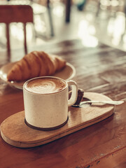 Wall Mural - A cup of coffee with latte art on top and butter  croissant