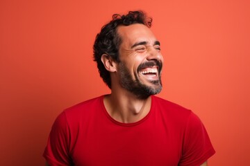 Wall Mural - Portrait of a smiling man in his 30s laughing while standing against solid color backdrop
