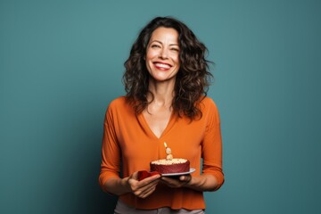Wall Mural - Portrait of a happy woman in her 40s holding a gift in solid color backdrop
