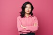 © Markus Schröder - Portrait of a content asian woman in her 20s with arms crossed in solid color backdrop