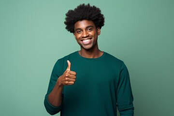 Canvas Print - Portrait of a glad afro-american man in his 20s showing a thumb up in front of solid color backdrop