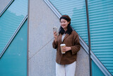 Fototapeta  - Stylish Woman Enjoying Coffee and Smartphone Outdoors