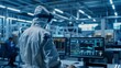 © Антон Сальников - A cleanroom in an electronics factory: a scientist in coveralls works on a computer, showing infographics and software system control screens, preparing electronics for medical applications.