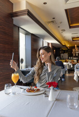 Wall Mural - Woman taking selfie in the restaurant while