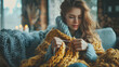 © Gohgah - A woman knitting on a cozy couch, highlighting the relaxation and satisfaction of this traditional and comforting hobby on Photo Stock.