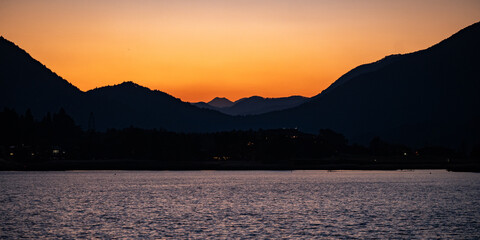 Wall Mural - a beautiful sunset over a lake with mountains in the background