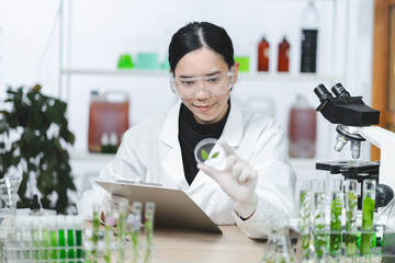 Wall Mural - A woman in a lab coat holding a clipboard and looking at a plant