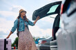 © Drazen - Happy woman taking suitcase out of the trunk on parking lot.