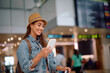 © Drazen - Young happy woman using smart phone at  airport.
