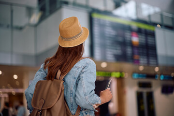 Wall Mural - Back view of tourist checking the flight schedule at airport.