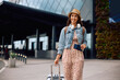 © Drazen - Happy woman pulling her travel bag while arriving at airport.