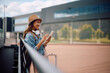 © Drazen - Happy female traveler using app on mobile phone at departure area.