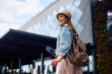 Wall Mural - Young happy woman at the airport going on a trip.