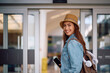 © Drazen - Happy female traveler with  passport at airport entrance looking at camera.