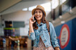 © Drazen - Cheerful woman talking on the phone at  airport.