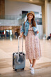 © Drazen - Full length of happy woman with suitcase walking at  airport.
