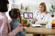 © sofiko14 - Mature experienced female doctor showing tablet with gastrointestinal tract image for treatment planning to little female child. Mother with little girl at appointment with family nutritionist.