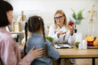 © sofiko14 - Mature woman with fresh apple in hand chatting with little female child and her mother in consulting room. Experienced medical specialist giving advice on improving diet by abundance of nutrients.