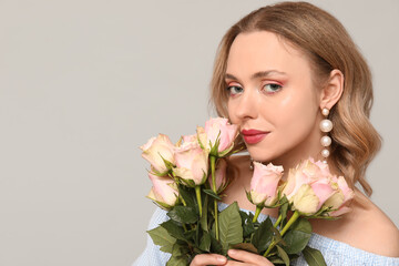 Poster - Pretty young woman with bouquet of beautiful roses on grey background