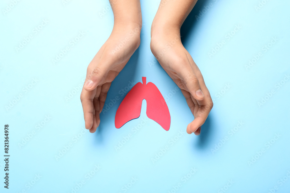 Female hands with paper lungs on blue background