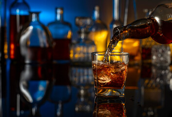 Poster - Whiskey is poured from a bottle into a glass with ice.