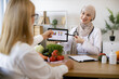 © sofiko14 - Arab female doctor makes treatment plan for gastrointestinal tract in modern clinic. Professional nutritionist tells patient about benefits of healthy diet while holding tablet with graphs in hands.