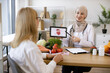 © sofiko14 - Beautiful adult woman at appointment with family nutritionist. Muslim experienced female doctor showing tablet with gastrointestinal tract image for treatment planning to mature lady.