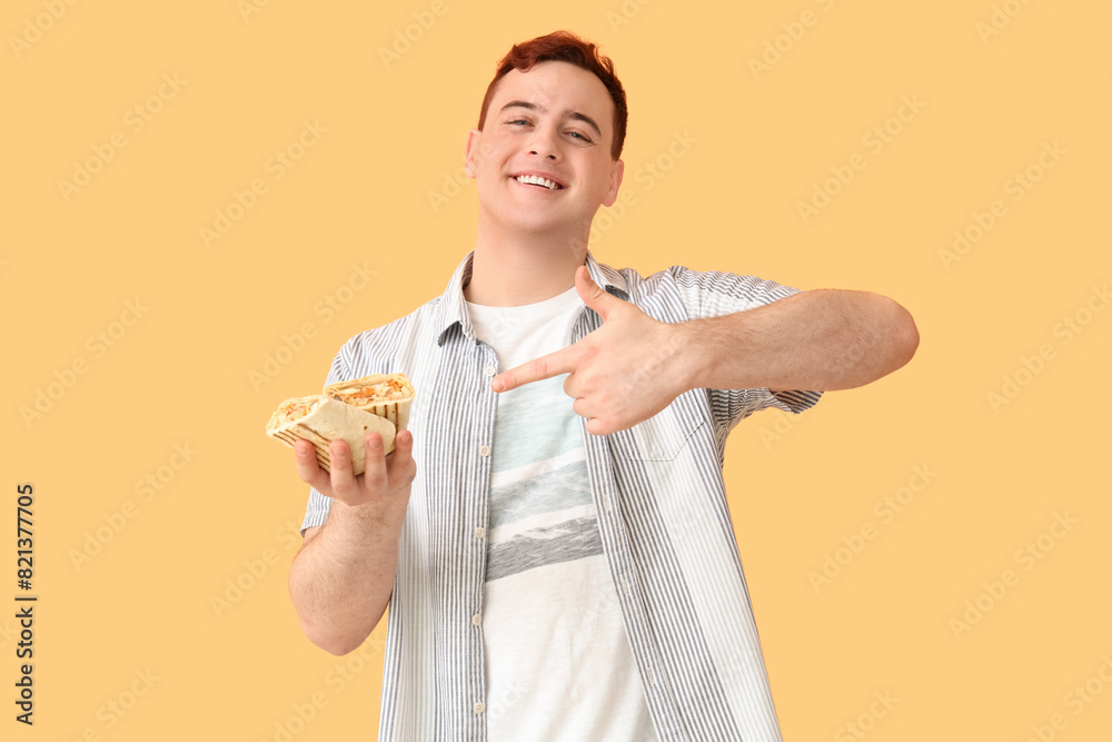 Young man smiling and pointing at doner kebab on beige background