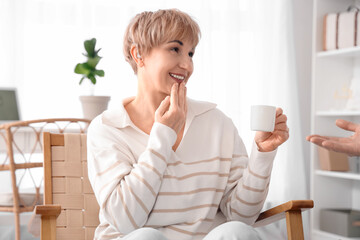 Canvas Print - Mature deaf mute woman with cup of coffee and her husband using sign language at home