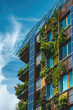 © dinastya - Modern sustainable building with solar panels, vertical garden with green plants.