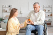 © Pixel-Shot - Senior man in wheelchair with caregiver taking pills at nursing home