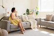 © Pixel-Shot - Young pretty woman with mobile phone sitting on sofa in living room