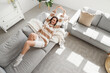 © Pixel-Shot - Young happy woman lying on sofa in light living room