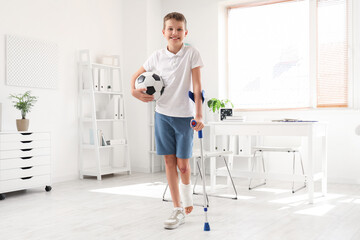 Sticker - Smiling little boy with crutch and soccer ball in clinic