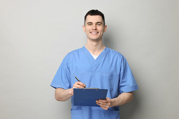 Sticker - Portrait of smiling medical assistant with clipboard on grey background