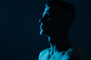 Poster - Muscular model sports young man on dark background. Fashion portrait of strong brutal guy. Male flexing his muscles.