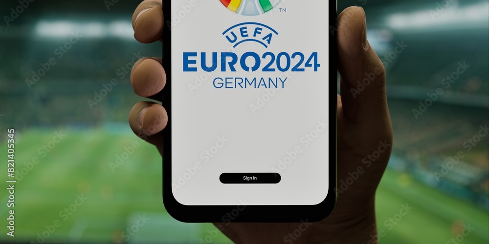 A hand holding a phone with the UEFA Euro 2024 app on a screen, against ...