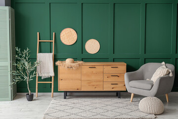 Interior of living room with cozy armchair, chest of drawers and olive tree