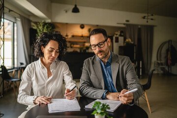 Man and woman colleagues hold documents and work together at cafe