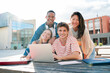 © Jose Calsina - A Diverse Group of Two Male and Two Female Students Gazing at the Camera While Collaboratively Studying Using a Laptop on the University Campus. Multiracial teenagers smiling and doing the homeworks