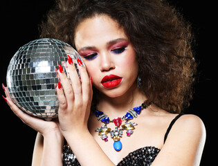 Portrait of young beautiful african woman with bright make up holding disco ball over black background