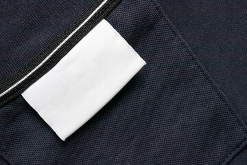 Sticker - Blank white laundry care clothes label on black shirt fabric texture background